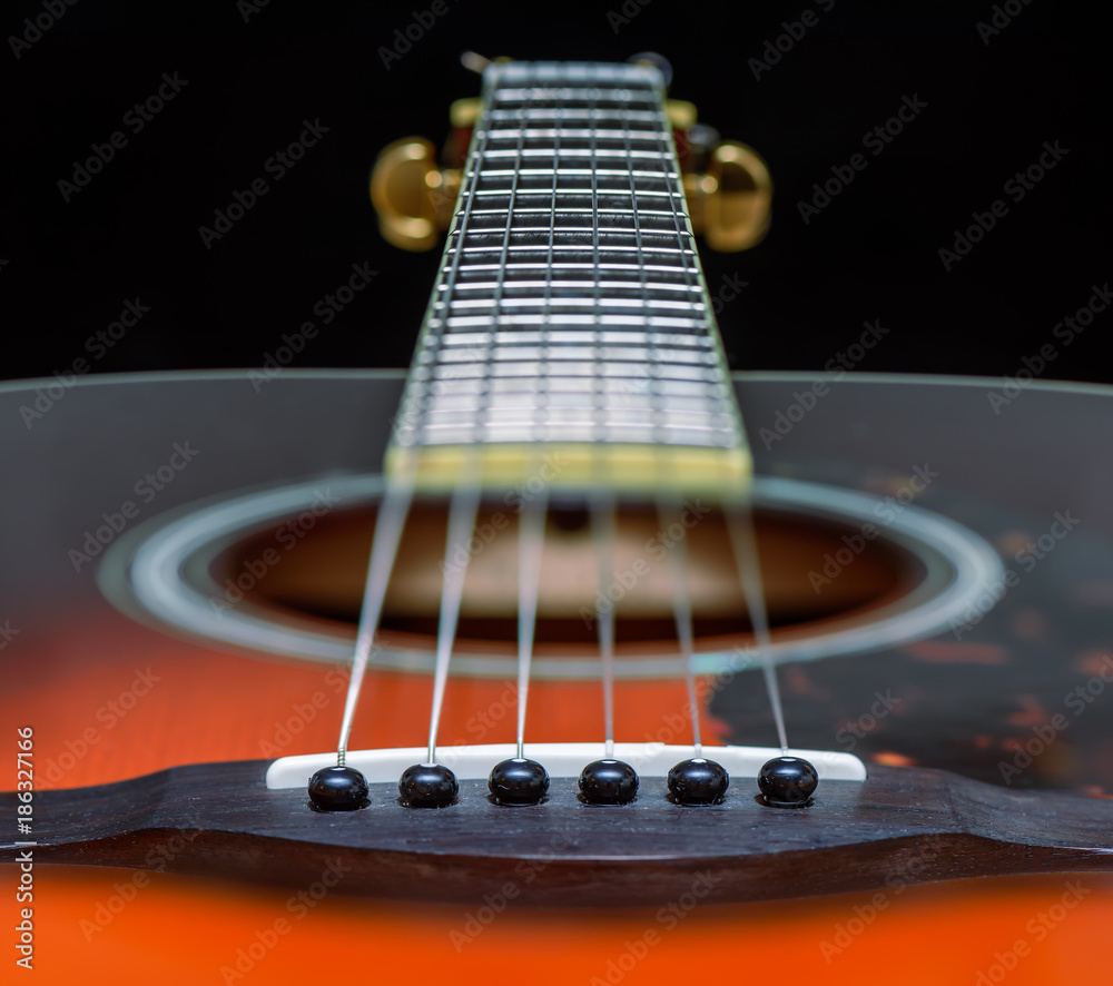 Fototapeta premium Acoustic orange guitar with strings close-up