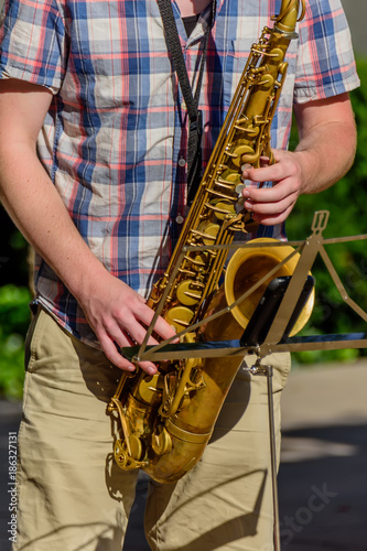saxophonist in checkered shirt playing on a yellow saxophone