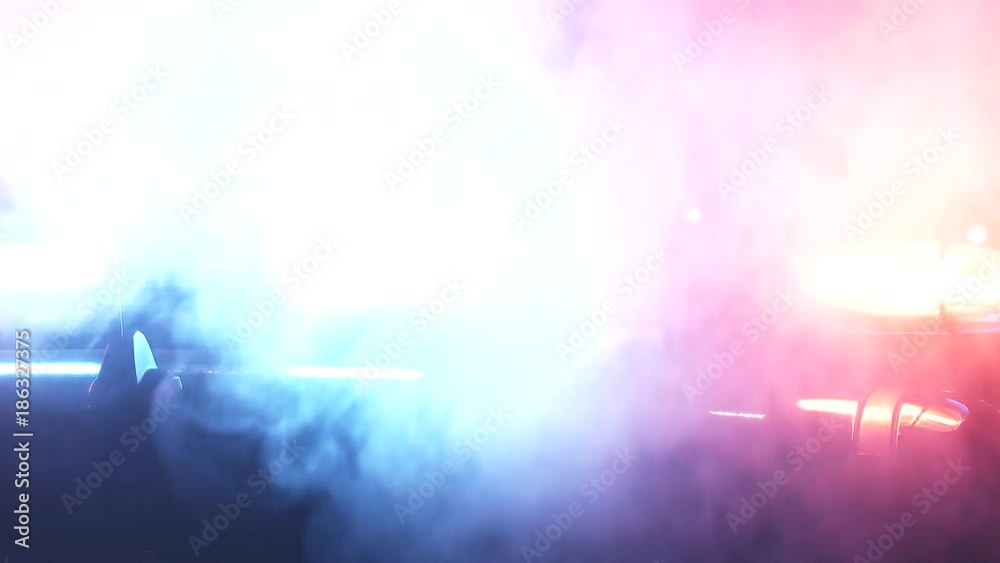 Close up on police car lights flashing at night with back lit smoke.