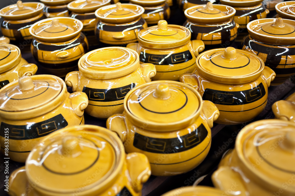 Ceramic mugs and bowls of yellow-brown color in the store on the counter stand in a pile. Sale, trade Ceramic mugs and bowls of yellow-brown color in the store on the counter stand in a pile. Sale, trade