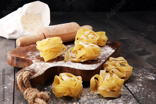 Making homemade pasta linguine on rustic kitchen table with flour, rolling pin and pasta