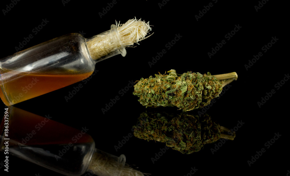 Medical Oil Cannabis - stick resin, apothecary bootle with oil and  marijuana flowers on the black mirror background. Stock Photo | Adobe Stock