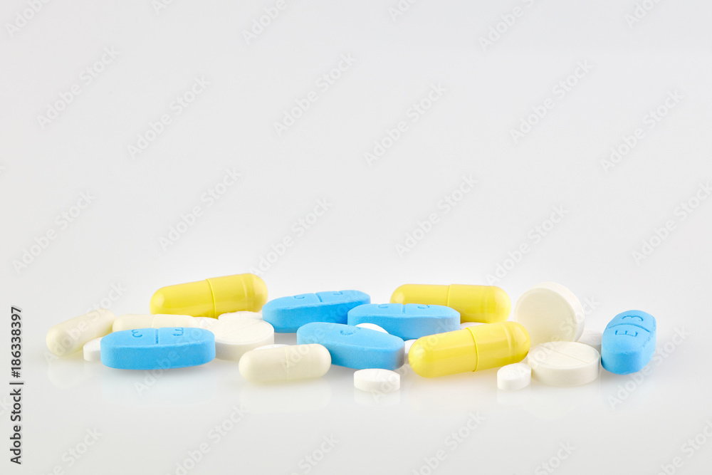 Assorted pharmaceutical medicine pills, tablets and capsules on white background. The cure for coronavirus.	