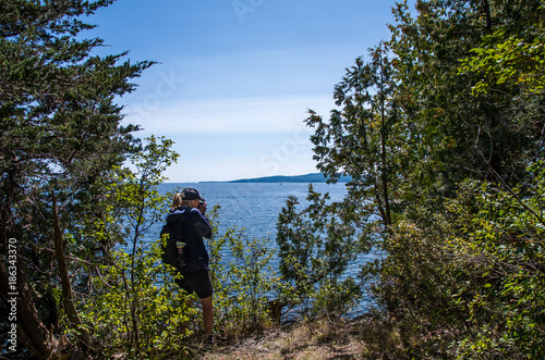 Woman taking a photo from the shore of Valcour Island