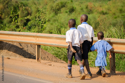 Three unidentified African Schoolchildren walking along the dangerous highway