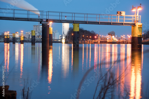 Footbridge in front of Weser weir (Weserwehr) and Weser lock (Weserschleuse), Bremen-Hemelingen, Germany at night with light reflections on water