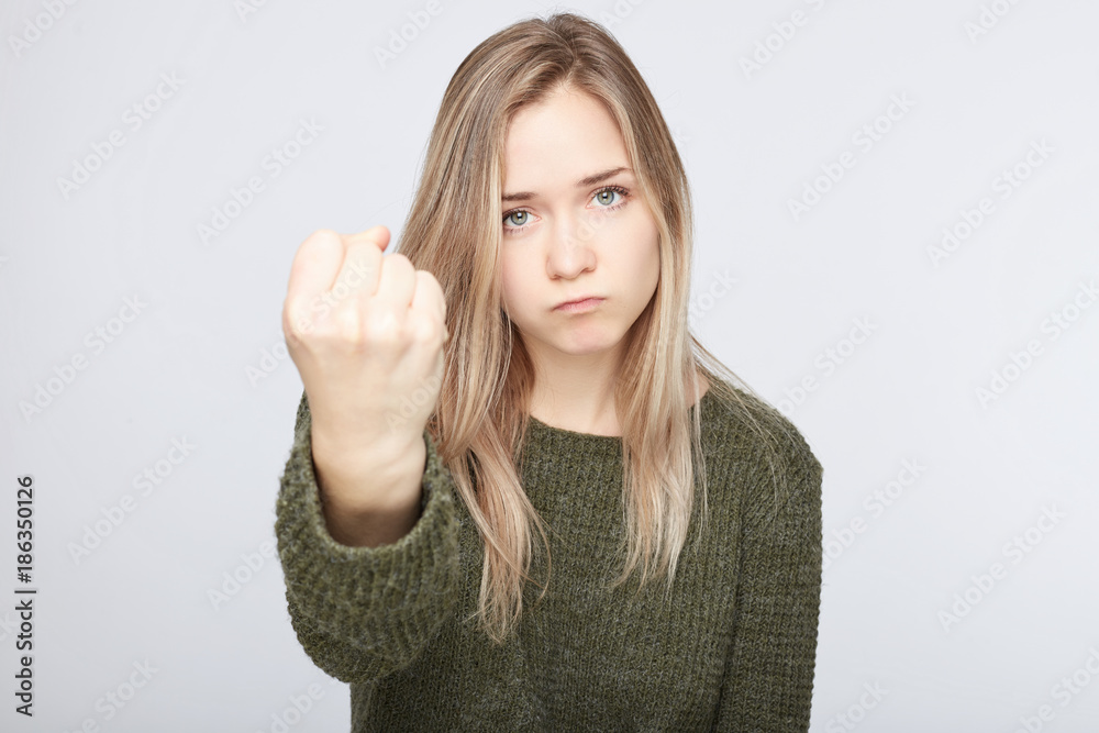 Outraged furious blond cute woman threatens with fist, has quarrel, screams in terror, shows her strength. Irritated annoyed Caucasian female being crazy, isolated over white wall studio background. Outraged furious blond cute woman threatens with fist, has quarrel, screams in terror, shows her strength. Irritated annoyed Caucasian female being crazy, isolated over white wall studio background.