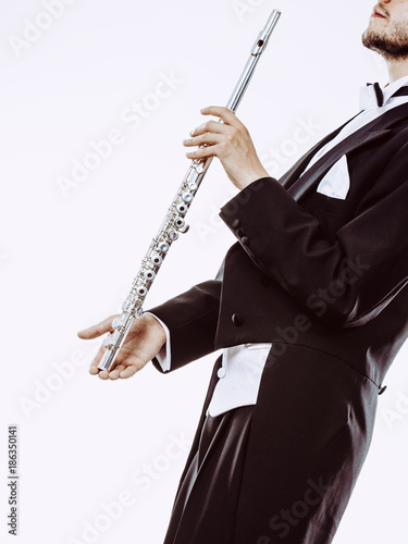 Male flutist wearing tailcoat holds flute