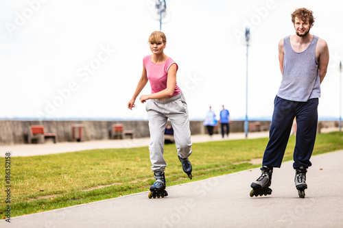 Friends rollerblading together have fun in park.