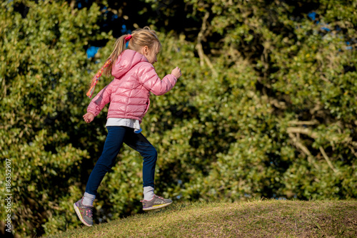 Little girl running on grassy hill in the park