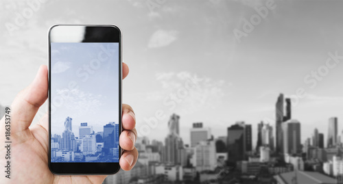 Hand holding mobile smart phone, black and white city background
