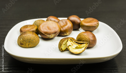 A cut ripe chestnut on a white plate on a table. photo