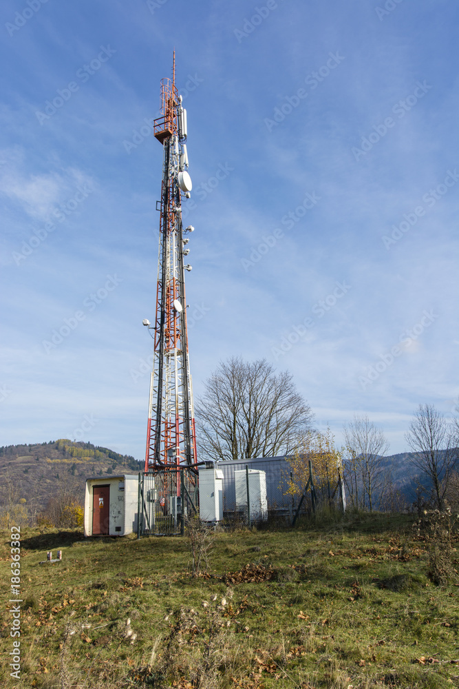 A transmitting mast with a small building and a blue sky in the background.