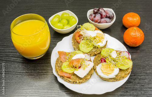 A plate with healthy rye bread sandwiches, fruit and juice for breakfast.