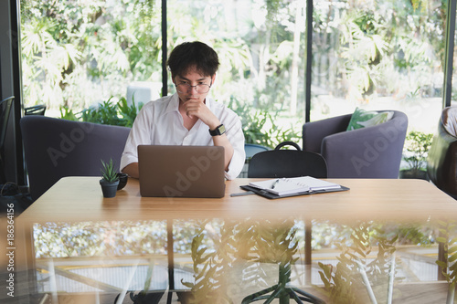 student using computer for learning leasson online at cafe. startup man working with laptop at office.  young male entrepreneur analyze financial data at workplace. business, education concept photo