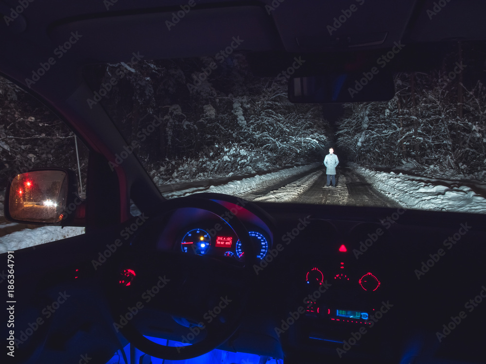 The man stand on the forest road near the car. inside view. evening night time