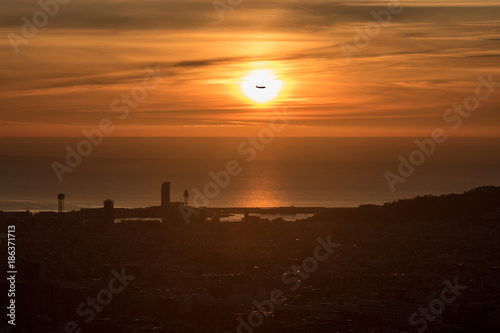 Avión atravesando el Sol en el amanecer de Barcelona
