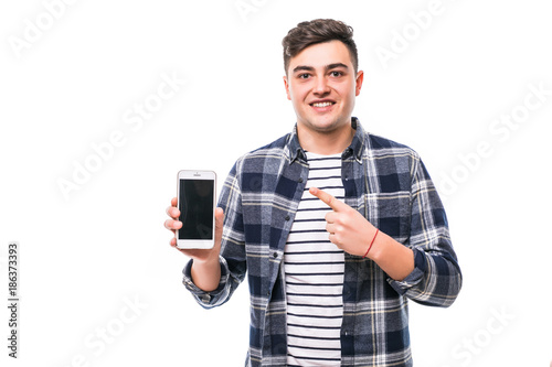 Smile young man is holding phone pointing on it with finger on white background