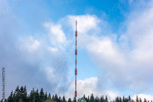 Very high transmission tower in front of cloudy blue sky