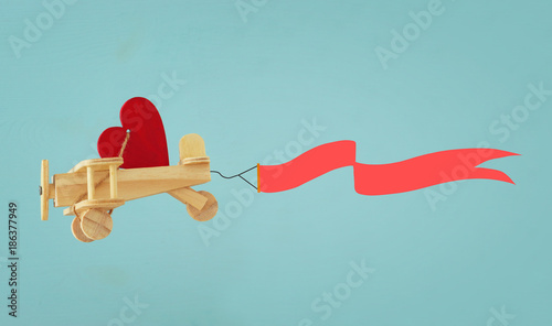 Valentine's day background. Wooden toy plane with heart and ribbon flying in the sky.