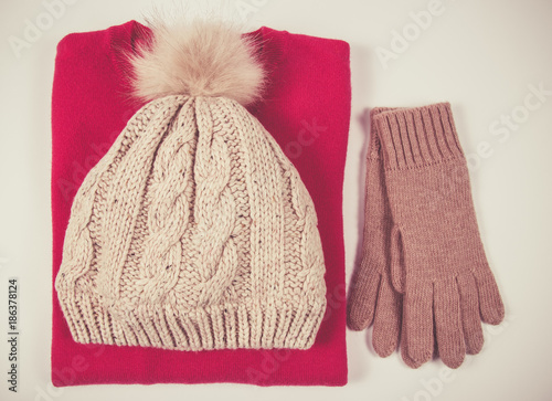Wool hat, sweater and gloves for winter weather on a white background.