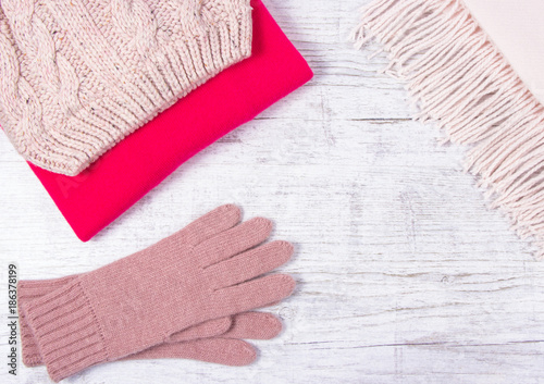Warm winter knitted clothes - hat, scarf, gloves on a wooden background.