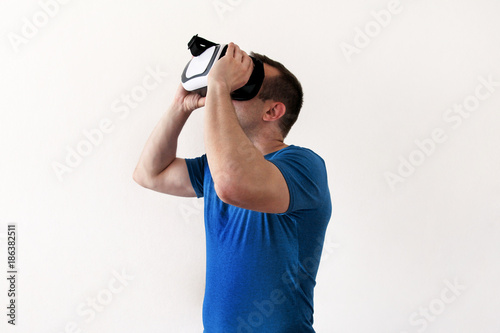 Man wearing and playing mobile game app on device virtual reality glasses on white background. Man action and using in virtual headset, VR box for use with smart phone. Contemporary technology concept