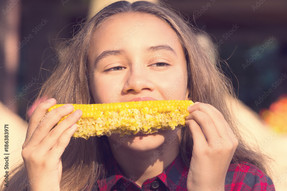 Girl eating sweet corn on the nature of the day Girl eating sweet corn on the nature of the day