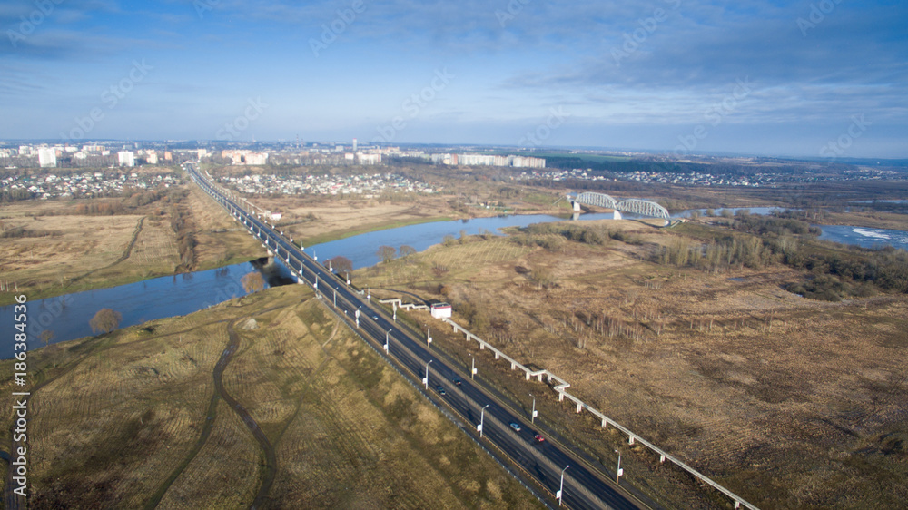 Photo of the city with an asphalt road. The landscape is photographed from a height. With a bridge and a river