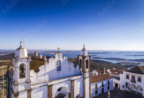 Aerial view of a church facade in the historic village of Monsaraz in Alentejo with the Alqueva dam reservoir on the background; Concept for travel in Portugal and most beautiful places in Portugal photo