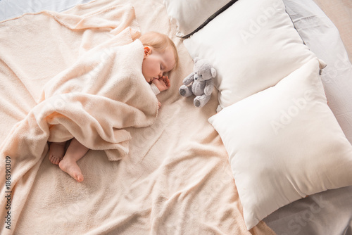 Top view of plump newborn napping on comfortable couch and nursing her finger photo
