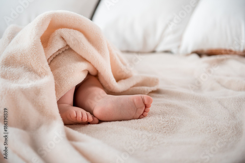 Small child legs seen from under the blanket on the comfortable bed. Copy space