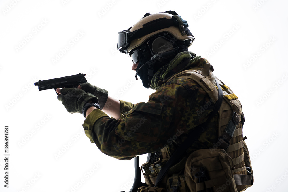 Fototapeta premium Side view serious defender wearing in ammunition firing with gun. Protection concept. Isolated