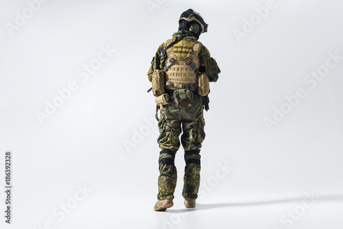 Full length soldier facing away while wearing protective military uniform. Maintenance concept photo