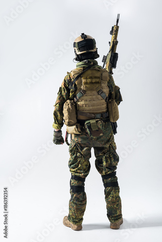 Obraz na plátně Full length peacemaker rising hand with assault rifle up while turning back to camera