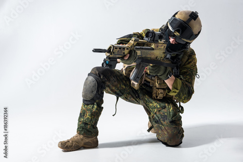 Portrait of serious defender looking at sniper scope of modern weapon. Military concept
