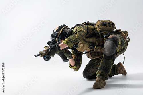 Full length serious defender firing with weapon while standing on knee. Sharpshooter concept