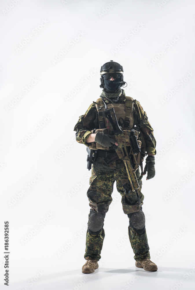 Full length portrait of calm peacemaker wearing military ammunition and holding modern weapon in hands. Defense concept