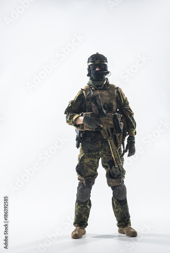 Full length portrait of calm peacemaker wearing military ammunition and holding modern weapon in hands. Defense concept