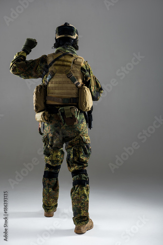 Full length man wearing ammunition while flourishing arm. He turning back to camera. Military concept