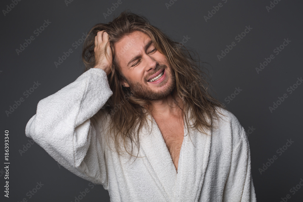 Waist up portrait of bushy guy holding one hand on head expressing negative emotions. Isolated on grey background Waist up portrait of bushy guy holding one hand on head expressing negative emotions. Isolated on grey background