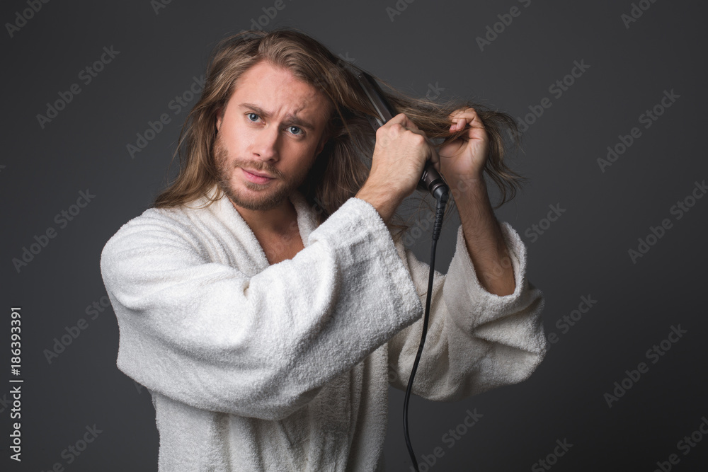 Waist up portrait of anxious male straightening his locks. Isolated on grey background Waist up portrait of anxious male straightening his locks. Isolated on grey background