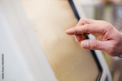 Verify orders. Close-up of fingers of man is touching display of self-service kiosk. Copy space in the left side