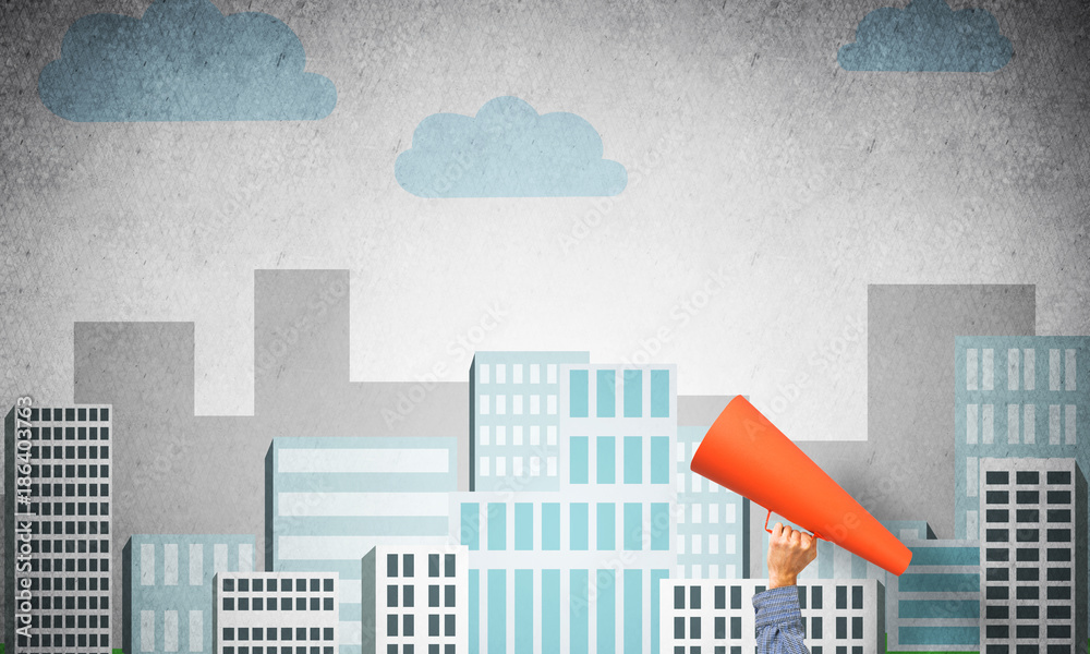 Hand of man holding orange paper trumpet against illustrated background