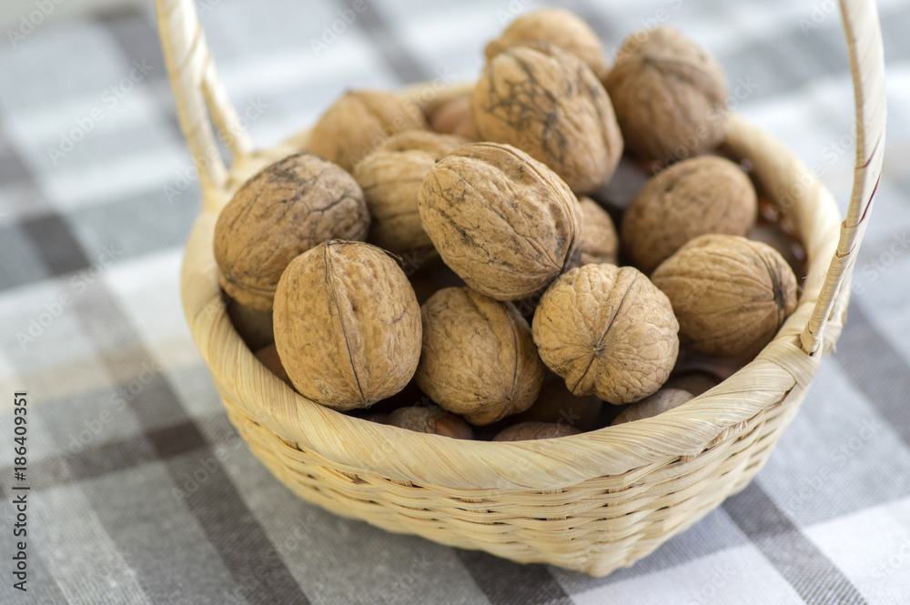 Walnuts in hard shells, pile on checkered tablecloth in creel Walnuts in hard shells, pile on checkered tablecloth in creel