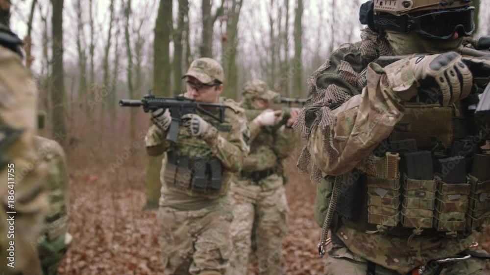 Group of armed young soldiers in a zone of armed conflict in uniform targeting with assault rifles in forest, slow motion, airsoft Group of armed young soldiers in a zone of armed conflict in uniform targeting with assault rifles in forest, slow motion, airsoft