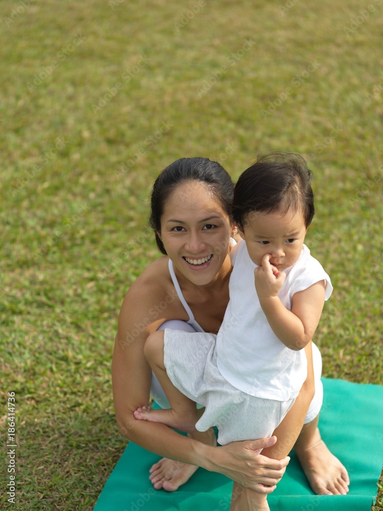 Asian chinese woman practising yoga outdoors with young baby girl Asian chinese woman practising yoga outdoors with young baby girl