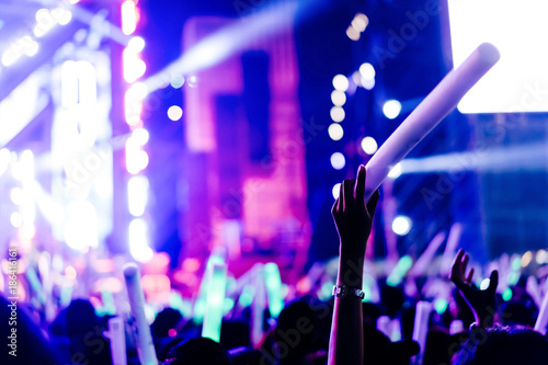 Crowd of hands up glow stick concert stage lights and people fan audience silhouette raising hands in the music festival rear view with spotlight glowing effect