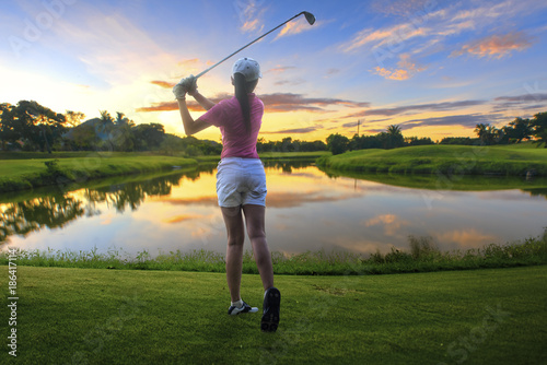 a woman golf player in an action of ene of downswing after hit the golf ball away from tee off to the fairway ahead by iron driver