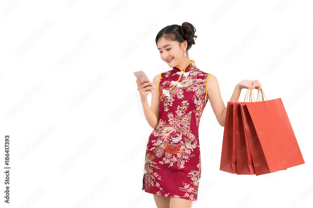 Asian woman wearing chinese dress with mobile smartphone shopping online technology holding shopping bag cheongsam,qipao concept on white isolated background Asian woman wearing chinese dress with mobile smartphone shopping online technology holding shopping bag cheongsam,qipao concept on white isolated background